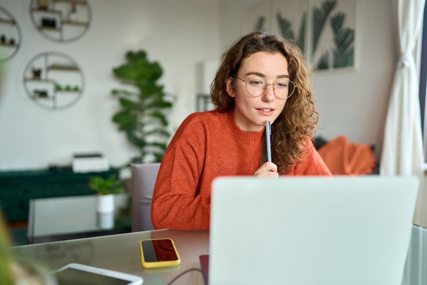 Schwarz/Weiß Foto einer telefonierenden Person, die am Laptop arbeitet und Cafe trinkt. 