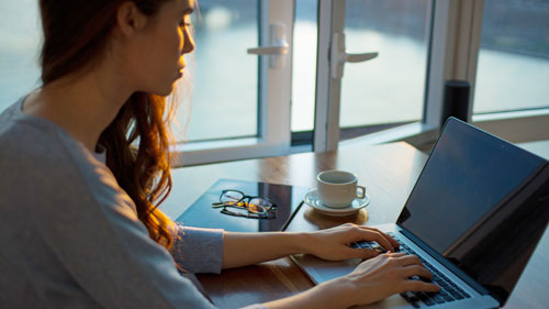 Frau vor Laptop folgt Online Info Session 