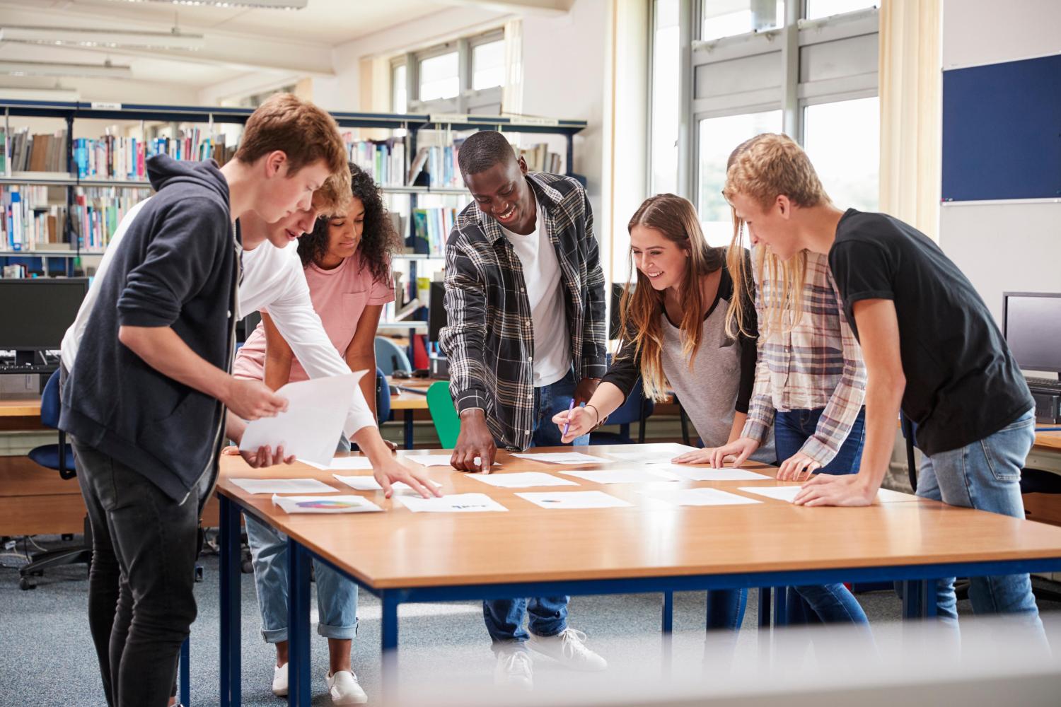 Ein Lehrender und eine Studierende des Tourismus Studiums am MCI in Innsbruck  besprechen an einem Tisch sitzend Aufgaben zu Eventmanagement 