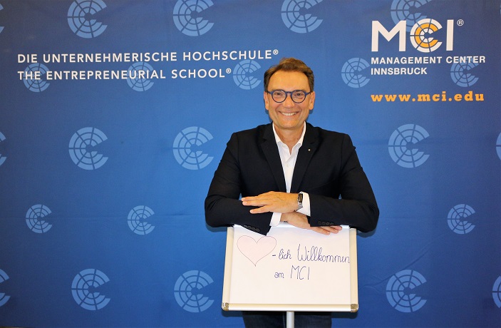 Dr. peter Mirski mit einem Willkommenschild für die neuen MCI Studenten.