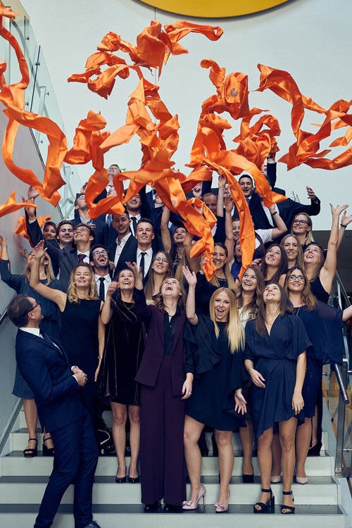 MCiT Graduates throwing their orange scarfs in the air.